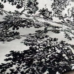 Image d'un tissu imprimé avec un motif détaillé de paysage naturel en noir et blanc. Design élégant et sophistiqué, idéal pour la décoration intérieure, apportant une touche artistique et moderne à votre espace. Parfait pour habiller coussins ou rideaux et ajouter du caractère à chaque pièce.