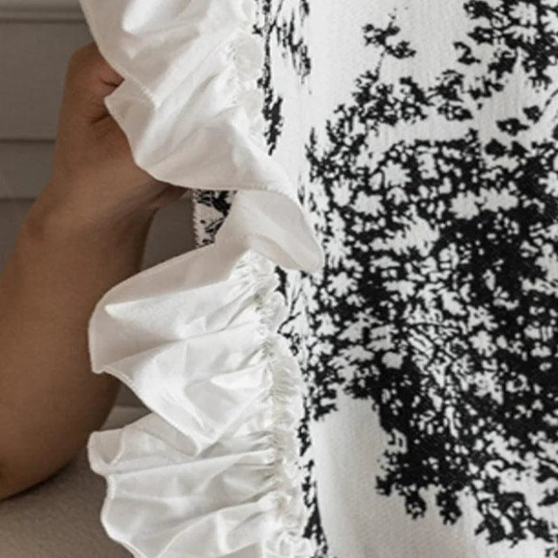 Blouse élégante avec imprimé noir et blanc, ornée de volants raffinés sur le côté, idéale pour un style chic et moderne. Ce vêtement est parfait pour rehausser votre garde-robe avec une touche de sophistication sans effort.
