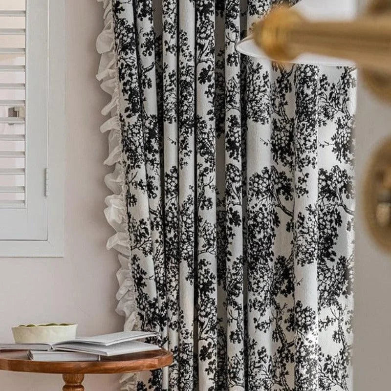 Rideau à motifs noirs sur fond blanc décorant un salon contemporain. Idéal pour ajouter une touche élégante et intemporelle à votre intérieur, ce rideau offre une belle intégration avec une décoration moderne. Parfait pour filtrer la lumière tout en créant une ambiance chaleureuse et accueillante.