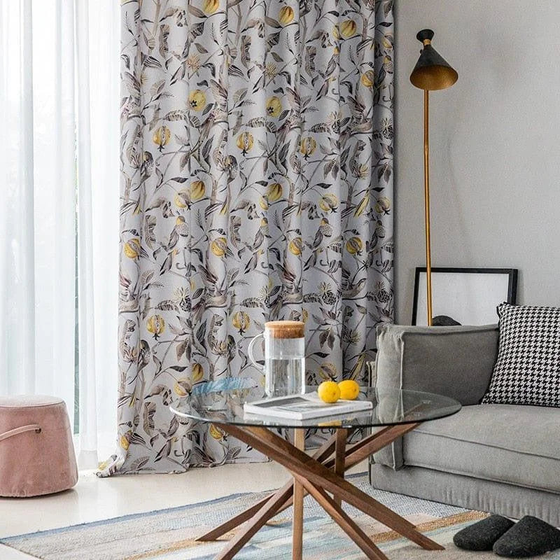 Décoration intérieure moderne avec rideaux à motif floral, lampe élégante et table basse en verre sur un tapis coloré, créant une ambiance chic et confortable. Parfaite intégration dans un salon accueillant, avec un canapé assorti et des touches de couleur. Parfaite pour apporter une touche de nature dans votre espace de vie.