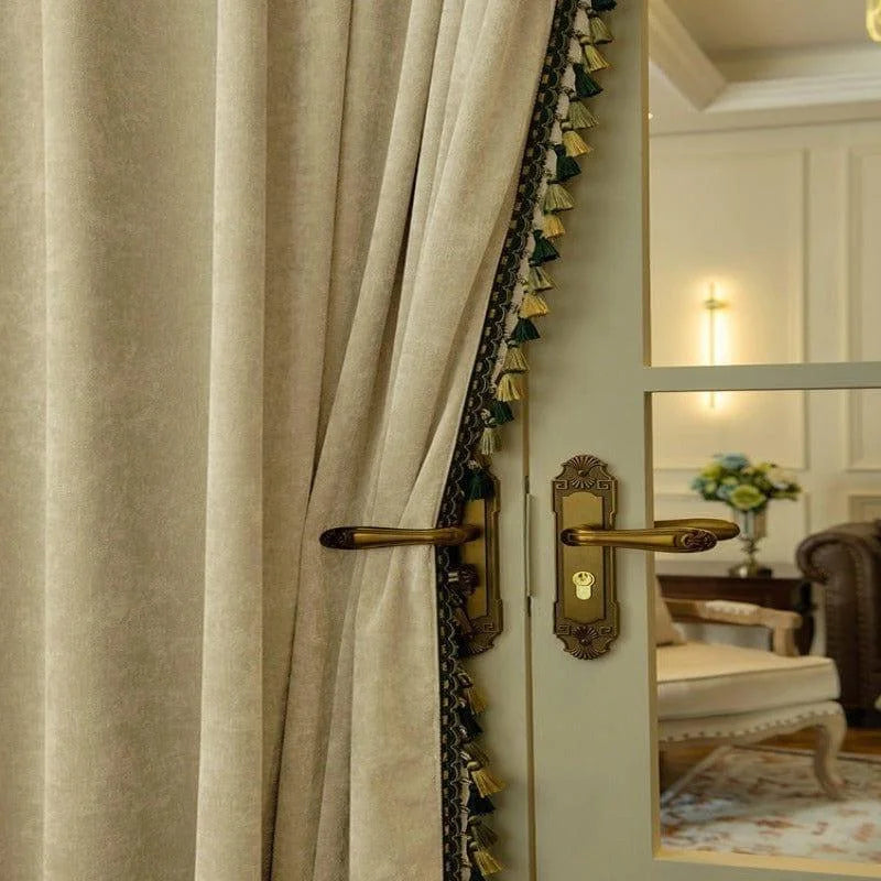 Rideau élégant avec franges décoratives suspendu devant une porte en bois avec des poignées dorées, créant une ambiance sophistiquée et chaleureuse dans un salon chic, éclairé par une lumière douce. Décoration intérieure, design raffiné et intimité assurée.