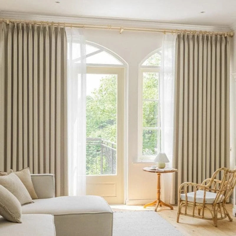 Chambre lumineuse avec rideaux élégants beige, offrant une ambiance apaisante et naturelle. Idéal pour créer une atmosphère raffinée et confortable dans un salon ou une chambre à coucher. Le mobilier en bois clair complète harmonieusement le design intérieur.