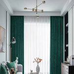 Salon élégant avec rideaux verts et lampadaire moderne. Canapé confortable orné de coussins colorés, table basse avec vase décoratif. Luminaire suspendu stylé, combinant design contemporain et douceur naturelle. Idéal pour une décoration intérieure harmonieuse. Parfait pour créer une ambiance chaleureuse et accueillante dans un espace de vie raffiné.