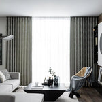 Salon moderne avec rideaux élégants encadrant une fenêtre lumineuse, mettant en valeur un décor intérieur épuré. Canapé confortable et table basse contemporaine assortis pour un espace de vie chic et harmonieux. Ambiance accueillante avec fauteuil design et accessoires décoratifs sophistiqués.