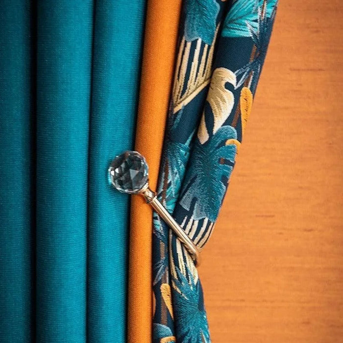 Rideaux élégants avec motifs tropicaux et couleurs vibrantes, ornés d'une embrasse décorative en cristal, apportant une touche sophistiquée et moderne à votre intérieur. Idéal pour ajouter une ambiance chaleureuse et stylée à votre salon ou chambre.