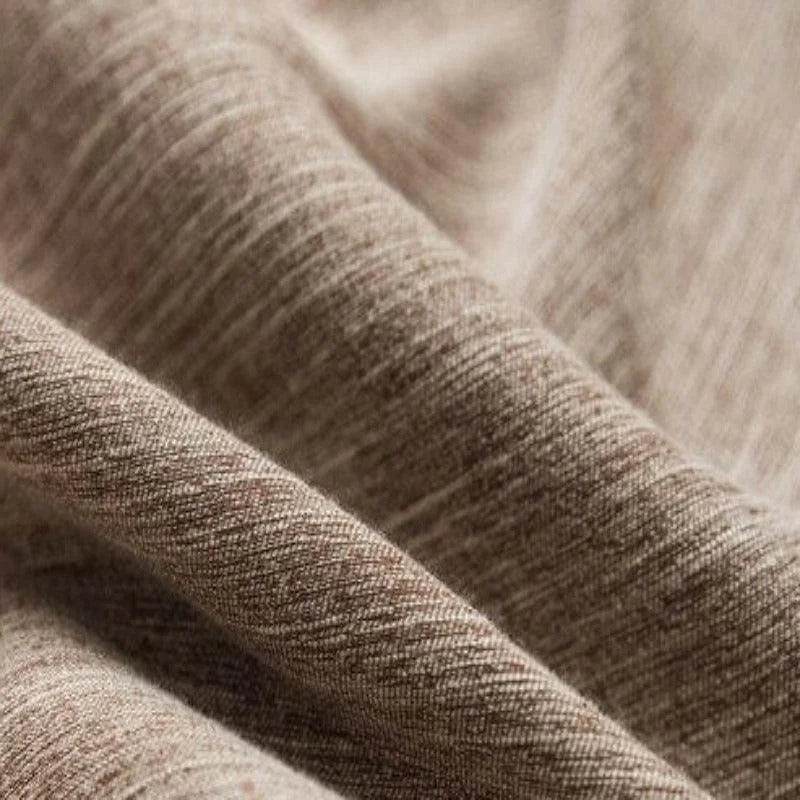 Texture de tissu beige en gros plan, montrant des motifs subtils et des ondulations délicates. Parfait pour l'ameublement ou les vêtements, ce tissu polyvalent offre une allure élégante et naturelle, idéale pour une décoration ou une mode intemporelle.