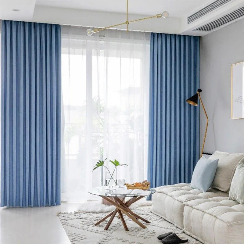 Rideaux bleus élégants dans un salon moderne, apportant une touche de couleur et de style à l'intérieur. Leur design ondulé et leur teinte apaisante créent une atmosphère accueillante, idéale pour se détendre. L'ajout d'une table basse moderne et d'un canapé confortable complète l'apparence contemporaine de cet espace de vie lumineux. Parfait pour améliorer la décoration intérieure de manière chic et sophistiquée.