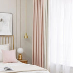 Chambre moderne et élégante avec un lit cosy agrémenté d'oreillers décoratifs rose, rideaux doux et lumineux, et éclairage suspendu doré. Décoration intérieure contemporaine idéale pour un espace chaleureux et accueillant.