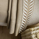 Plaid beige élégant avec motif décoratif, posé sur un fauteuil confortable. Accessoire idéal pour salon moderne, apportant chaleur et style à votre décoration intérieure. Parfait pour les soirées cocooning.