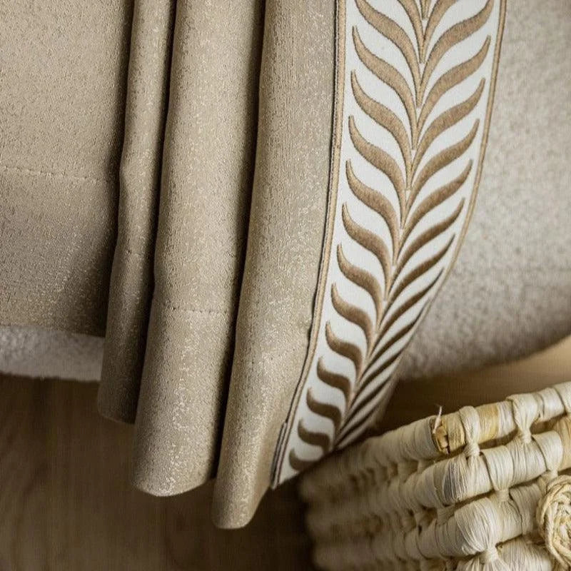 Plaid beige élégant avec motif décoratif, posé sur un fauteuil confortable. Accessoire idéal pour salon moderne, apportant chaleur et style à votre décoration intérieure. Parfait pour les soirées cocooning.