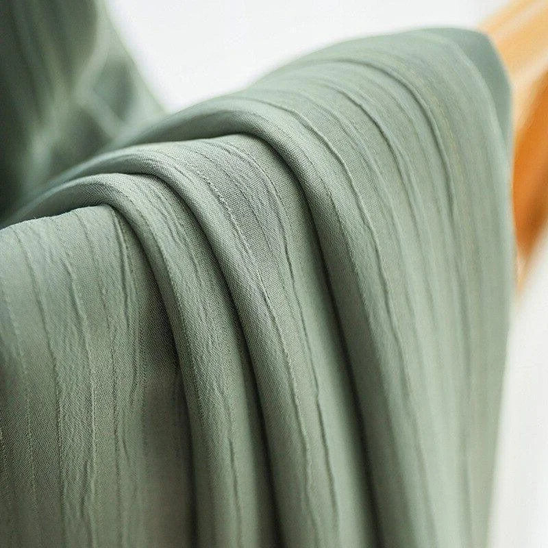 Plaid élégant vert doux drapé sur une surface en bois, conçu pour offrir confort et style à votre intérieur. Parfait pour ajouter une touche naturelle et apaisante à votre décoration. Idéal pour les soirées fraîches.