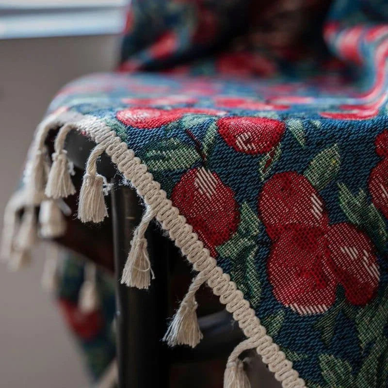 Image présentant un tapis décoratif avec un motif de fruits rouges et des feuilles vertes, orné de franges blanches. Ce textile coloré ajoute une touche élégante et originale à votre intérieur, idéal pour rehausser la décoration de votre salon ou chambre. Accessoire parfait pour créer une ambiance chaleureuse et accueillante.