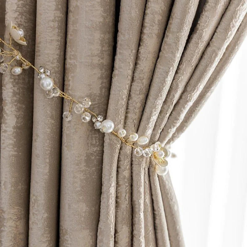 Rideaux élégants couleur taupe agrémentés d'une embrasse décorative perlée. Design raffiné pour orner le salon ou la chambre, apportant une touche de sophistication et d'élégance à la décoration intérieure. Idéal pour des ambiances chics et contemporaines.