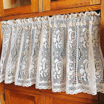 Rideau blanc décoratif au style vintage avec motifs floraux ajourés, idéal pour embellir une cuisine ou une salle à manger. Fixé sur une tringle en bois, il offre une touche d'élégance et de lumière douce à votre intérieur. Accessoire parfait pour un aménagement de maison chaleureux et classique.