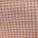 Texture à motif pied-de-poule orange et blanc, idéale pour décoration intérieure ou création de vêtements, ajoutant une touche élégante et contemporaine à tout projet.
