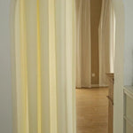Rideaux beiges élégants ornant une entrée voûtée, apportant luminosité et chaleur à un espace intérieur décoré avec goût. Ideal pour créer une séparation subtile entre différentes pièces.