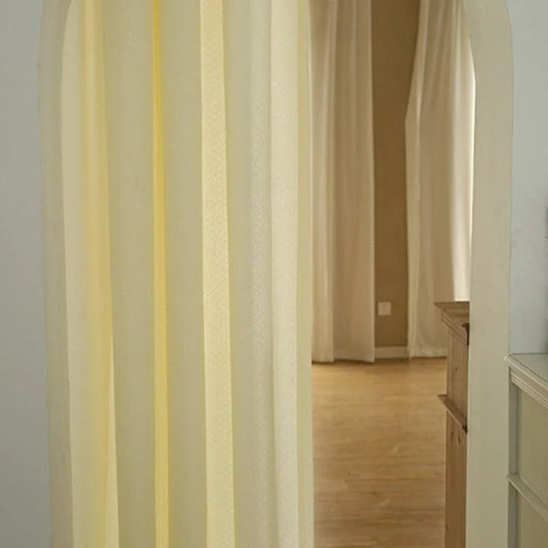 Rideaux beiges élégants ornant une entrée voûtée, apportant luminosité et chaleur à un espace intérieur décoré avec goût. Ideal pour créer une séparation subtile entre différentes pièces.