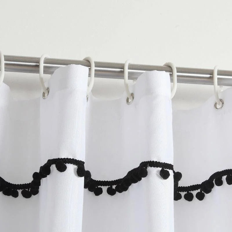 Rideau de douche blanc avec franges décoratives noires, suspendu à une tringle en métal argenté. Accessoire de salle de bain moderne ajoutant une touche élégante et contrastée à votre décoration intérieure. Facile à installer avec des anneaux de suspension inclus, idéal pour embellir votre espace de douche.