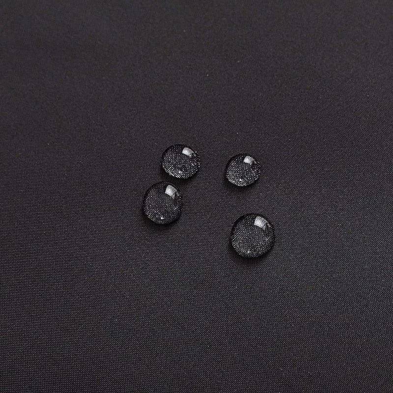 Image d'un tissu noir avec des gouttelettes d'eau, illustrant l'aspect déperlant et résistant à l'eau, parfait pour les applications extérieures et les vêtements fonctionnels. Idéal pour les conditions météorologiques humides, ce tissu allie style et efficacité pour garder au sec.