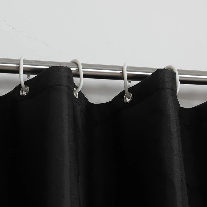 Rideau noir élégant accroché à une tringle métallique avec des anneaux blancs, idéal pour ajouter une touche moderne et sophistiquée à votre intérieur. Accessoire parfait pour la décoration de la maison, convenant aussi bien aux salons qu’aux chambres à coucher.