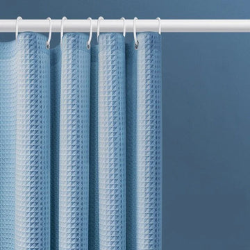 Rideau de douche bleu moderne avec motif texturé, idéal pour une salle de bain contemporaine. Dispose d'anneaux blancs assortis pour une fixation facile sur la tringle. Élément de décoration fonctionnel pour protéger des éclaboussures tout en ajoutant du style à votre espace.
