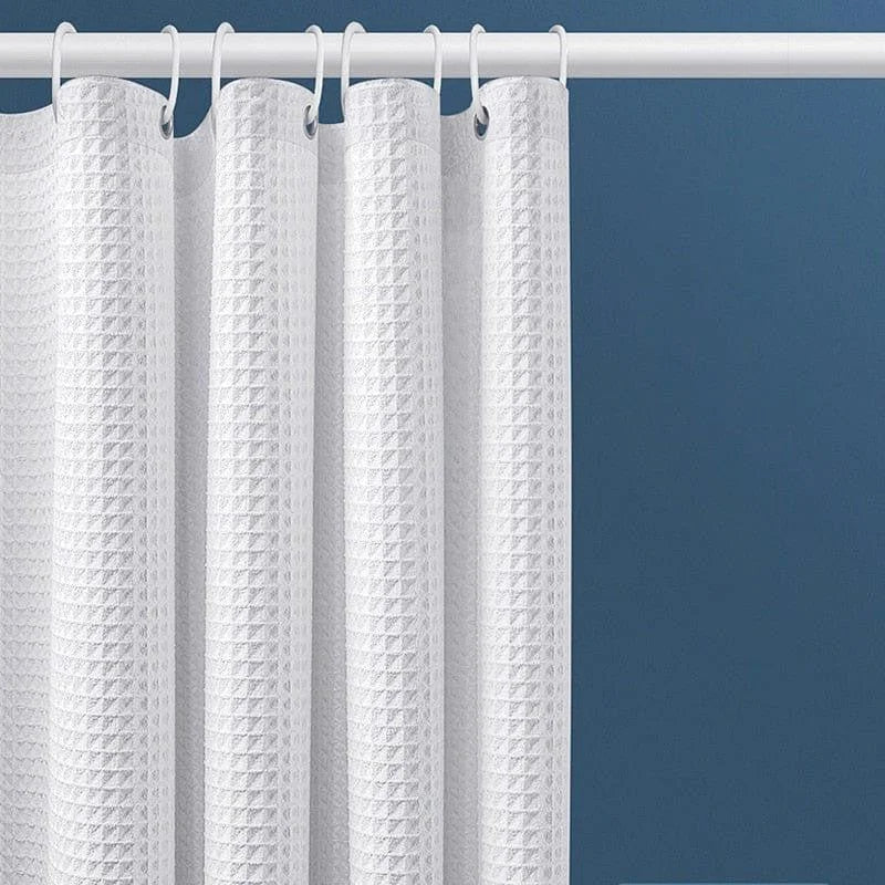 Rideau de douche blanc avec texture gaufrée, suspendu à une tringle sur fond de mur bleu. Idéal pour ajouter une touche moderne et élégante à votre salle de bain tout en assurant intimité et confort.