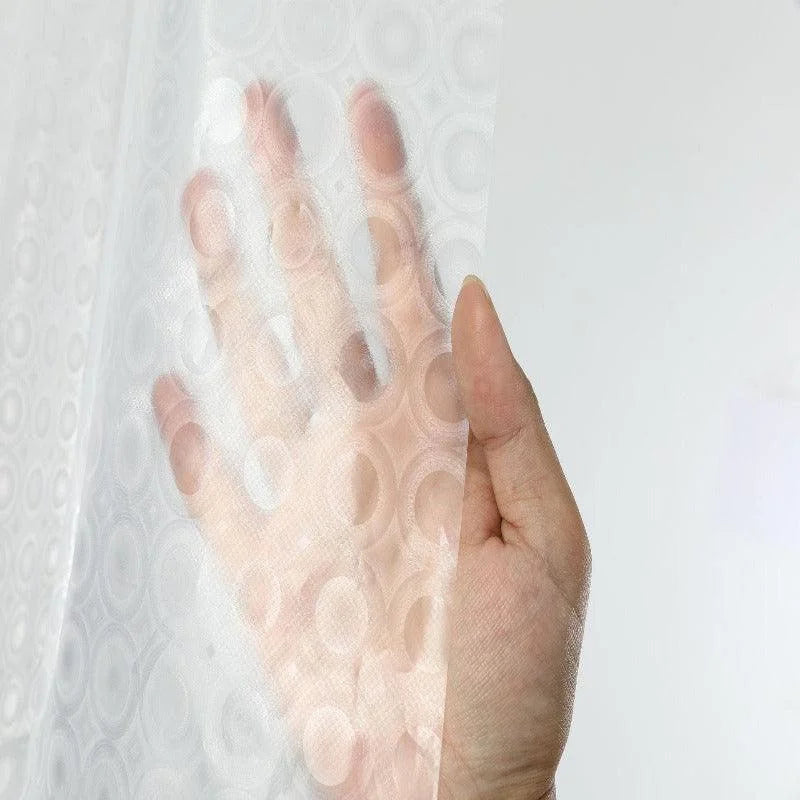 Main montrant un film protecteur transparent avec motifs circulaires, idéal pour l'intimité et la décoration des espaces intérieurs. Produit parfait pour améliorer le design tout en préservant la luminosité naturelle.
