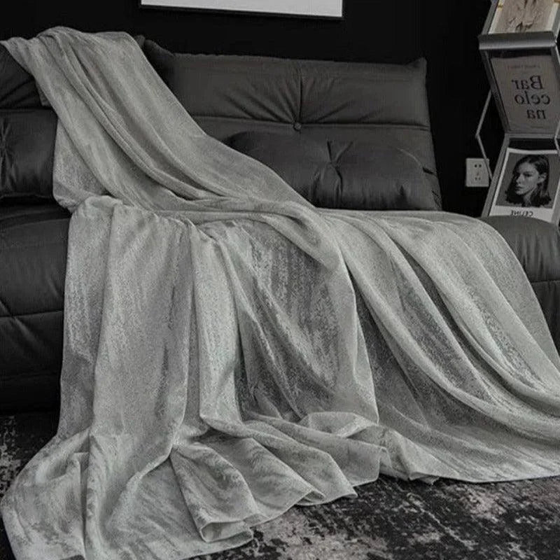Plaid élégant gris sur canapé noir, ajoutant une touche de sophistication à votre salon moderne. Parfait pour créer une ambiance chaleureuse et confortable, ce plaid rehausse la décoration grâce à son design chic et intemporel. Idéal pour se détendre lors des soirées fraîches.