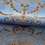 Image d'un tissu bleu avec un motif brodé doré et brun, idéal pour la décoration intérieure, apportant une touche d'élégance et de raffinement à votre espace de vie. Design complexe et ornemental, parfait pour des projets de couture ou d'ameublement sur mesure.