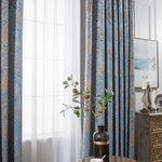 Rideaux élégants bleus avec motifs décoratifs dans un salon moderne. La lumière naturelle traverse les voilages, créant une atmosphère chaleureuse. Décoration intérieure raffinée avec vase et tableau minimaliste. Idéal pour ajouter une touche chic et stylée à n'importe quelle pièce.