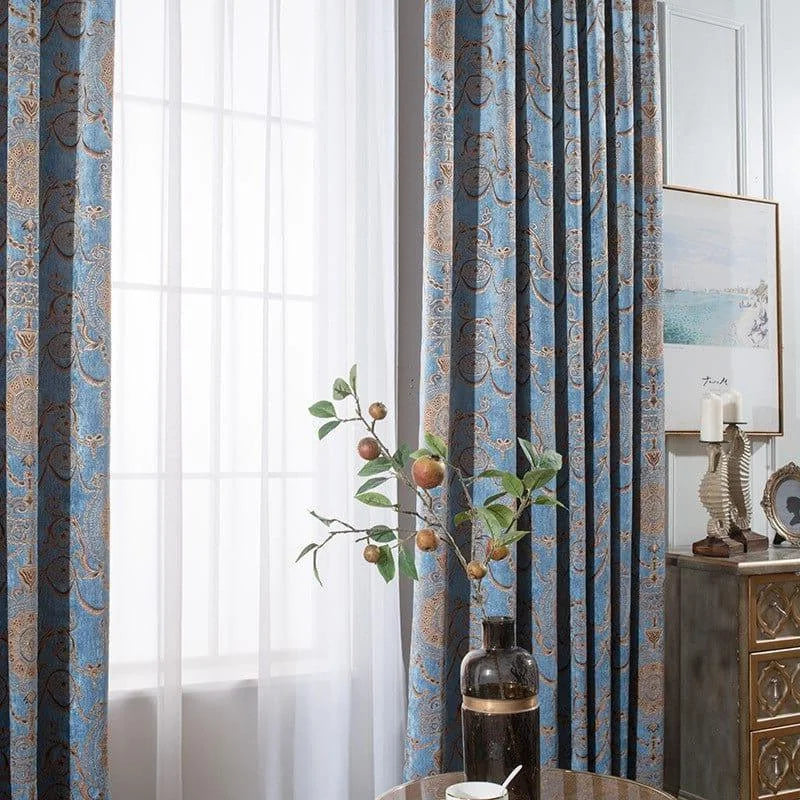 Rideaux élégants bleus avec motifs décoratifs dans un salon moderne. La lumière naturelle traverse les voilages, créant une atmosphère chaleureuse. Décoration intérieure raffinée avec vase et tableau minimaliste. Idéal pour ajouter une touche chic et stylée à n'importe quelle pièce.