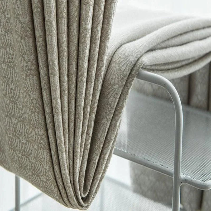 Couverture beige élégante posée sur une chaise moderne en métal, parfaite pour ajouter une touche de sophistication à votre salon ou chambre à coucher.