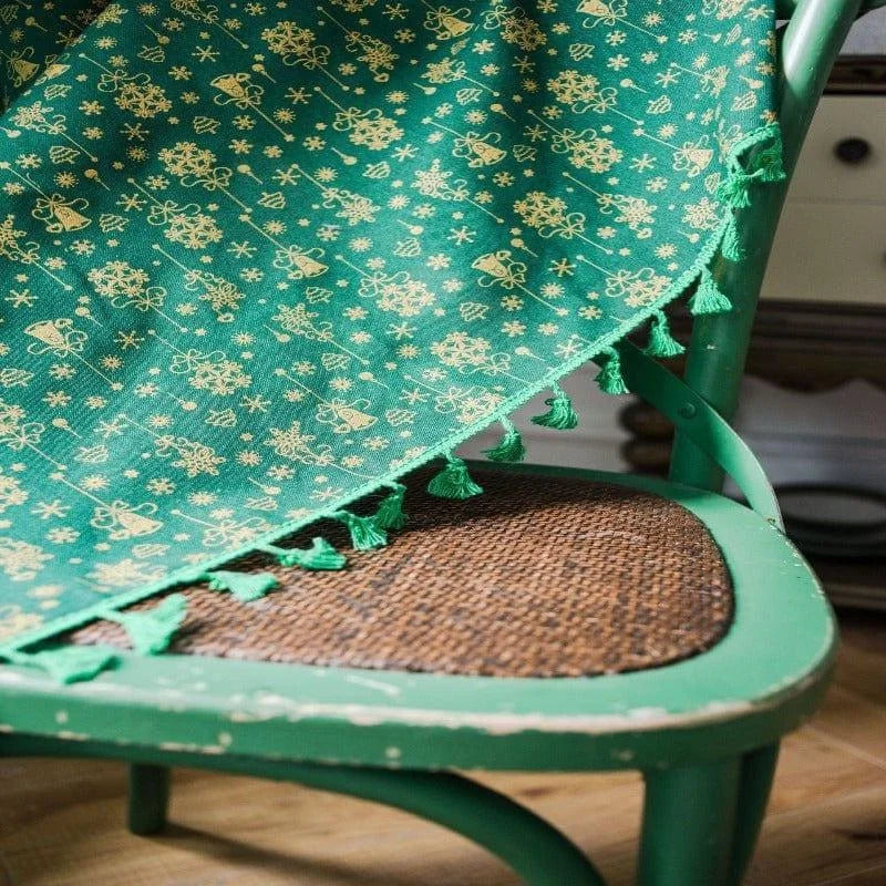 Chaise en bois vert avec une couverture verte décorée de motifs festifs dorés, ornée de franges. Idéale pour ajouter une touche de style à votre décoration intérieure, parfaite pour les espaces de vie chaleureux.