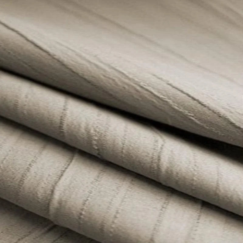 Empilement de tissu beige plissé avec motif subtil, idéal pour la décoration intérieure ou l'ameublement. Parfait pour apporter une touche d'élégance et de douceur à votre espace de vie.