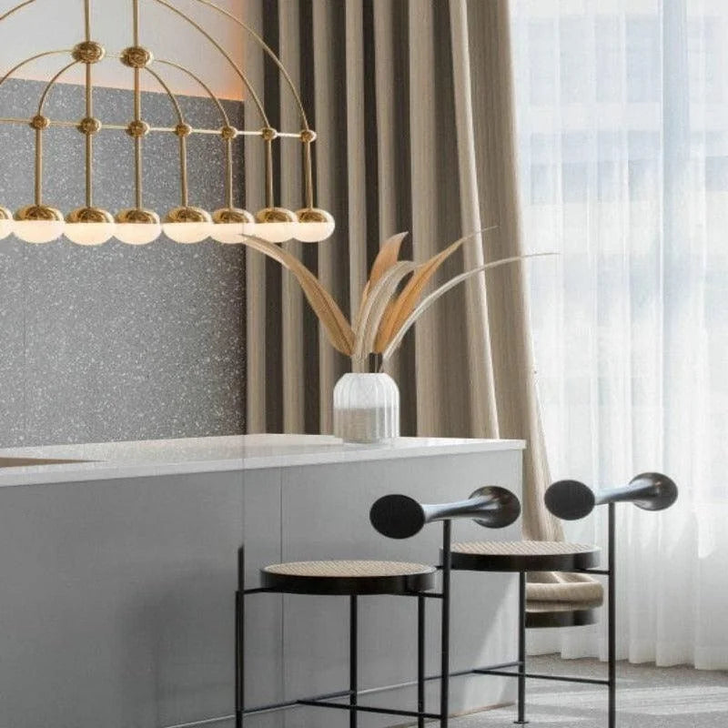 Salle à manger moderne avec suspensions élégantes et tabourets minimalistes noirs. Décoration contemporaine mise en valeur par un éclairage raffiné et un vase avec des branches décoratives. Design intérieur chic et épuré.