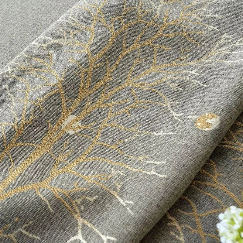 Image d'un tissu décoratif orné de motifs d'arbres dorés sur fond gris. Parfait pour ajouter une touche élégante à votre intérieur, ce design raffiné allie modernité et nature. Adapté pour des rideaux, coussins ou autres usages décoratifs.