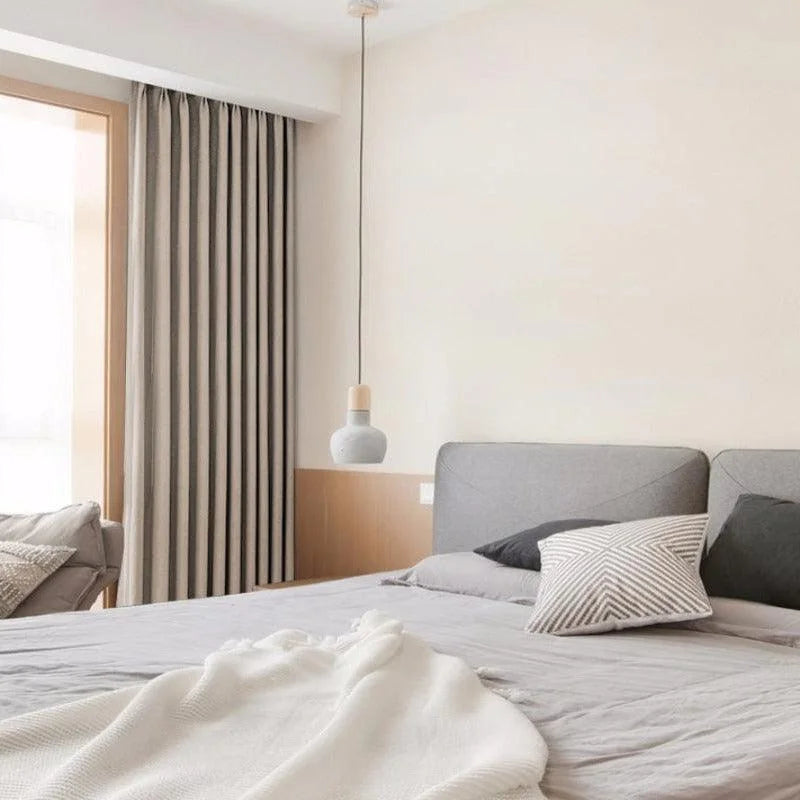 Chambre moderne et élégante avec un lit confortable équipé de coussins décoratifs. Les rideaux occultants ajoutent une touche de style et de praticité. Lampe suspendue design pour un éclairage d'ambiance sophistiqué. Atmosphère apaisante idéale pour une relaxation optimale.