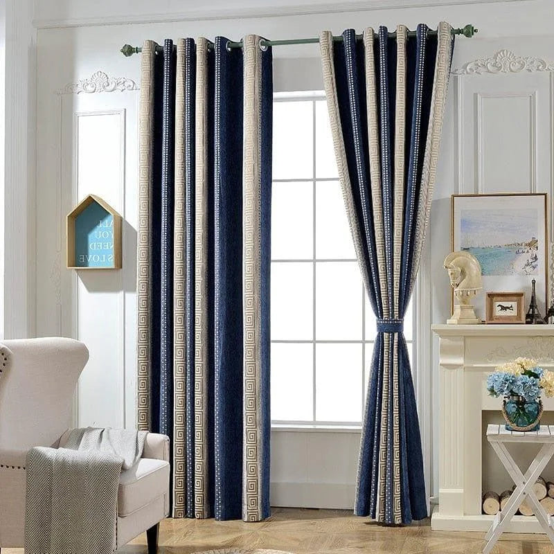 Rideaux élégants bleus et beiges suspendus dans un salon lumineux avec une cheminée décorative. Accessoires de décoration tels qu'un cadre photo, une statue et un vase de fleurs sur le manteau de cheminée. Fenêtre encadrée d'un motif classique géométrique, ajoutant une touche sophistiquée à la pièce. Fauteuil confortable avec un plaid gris en premier plan.