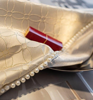 Élégant tissu brodé avec motifs géométriques et décoration perles, accompagné d'un rouge à lèvres rouge. Accessoire idéal pour un style raffiné et chic, parfait pour rehausser votre intérieur avec une touche de luxe et de sophistication.