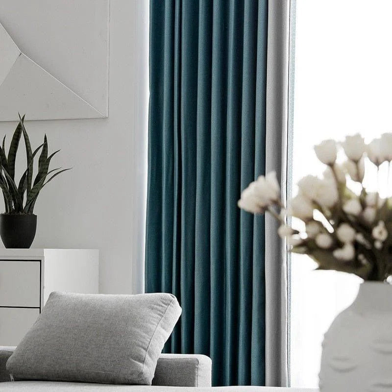 Rideaux élégants bleus pour salon moderne, ajoutant une touche chic à la décoration intérieure. Harmonisez votre espace avec ces rideaux qui complètent parfaitement le mobilier gris clair et les détails de plantes vertes, créant une ambiance accueillante et contemporaine. Idéal pour une maison design et stylée.