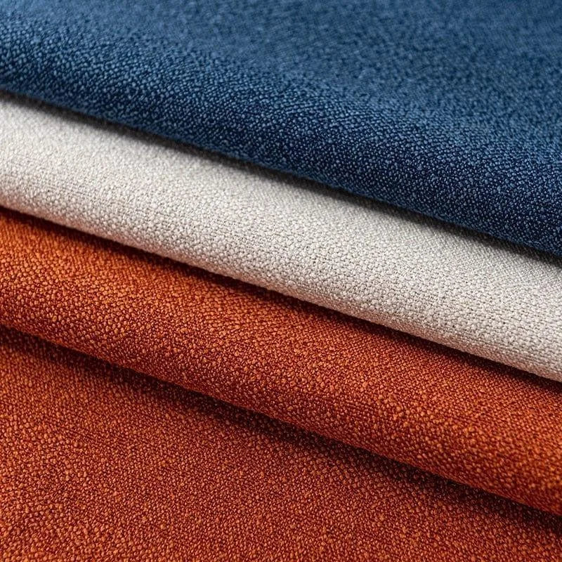 Tissus décoratifs empilés en trois couleurs élégantes : bleu marine, blanc cassé et orange rouille. Idéal pour la décoration intérieure ou la confection de vêtements. Ces tissus offrent une palette de couleurs riches et chaleureuses pour tout projet créatif.