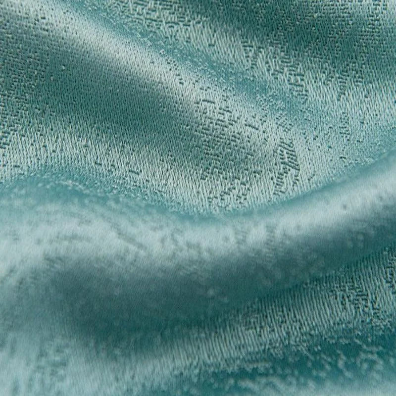 Texture de tissu bleu pâle avec un motif texturé subtil, idéal pour des projets de décoration intérieure élégante et moderne.