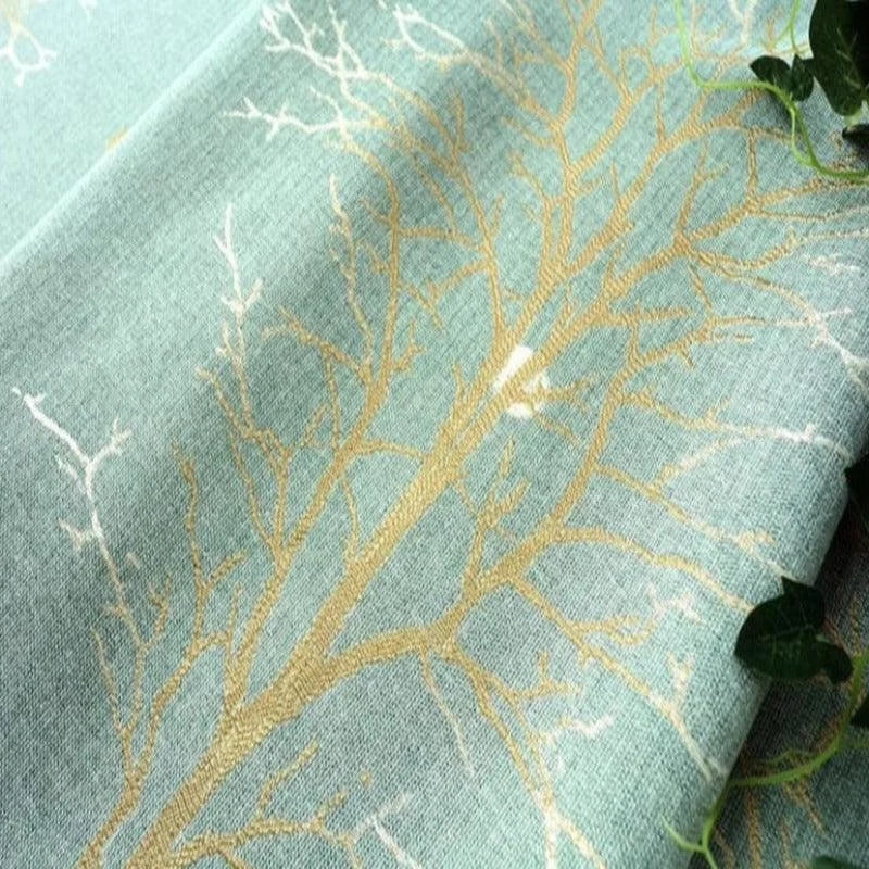Tissu décoratif bleu avec motif de branches dorées, idéal pour ajouter une touche naturelle et élégante à votre intérieur. Parfait pour confectionner des rideaux ou coussins.