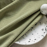 Serviette vert clair avec motif géométrique élégamment posée sur une assiette blanche au design à motifs noirs. Accessoire décoratif idéal pour un intérieur moderne et sophistiqué, ajoutant une touche de style et de raffinement à votre table. Parfait pour une décoration de table unique et contemporaine.