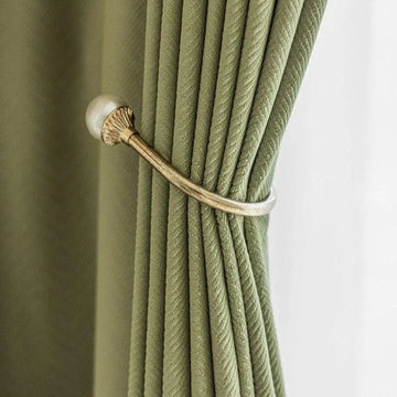 Attache-rideau élégante en métal doré avec rideau vert, idéale pour ajouter une touche sophistiquée à votre décoration intérieure, tout en optimisant la gestion de la lumière dans vos pièces.