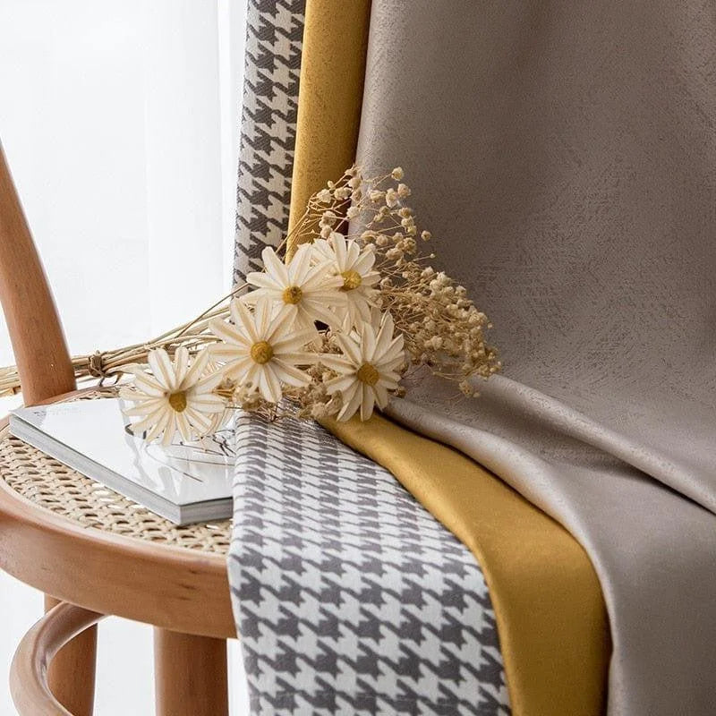 Des tissus élégants sont drapés sur une chaise en bois avec un motif pied-de-poule gris et une teinte jaune vive. Un bouquet de fleurs séchées et blanches repose délicatement sur l'assise, apportant une touche naturelle et décorative. Ce style raffiné et moderne est idéal pour inspirer votre décoration intérieure, ajoutant sophistication et charme à n'importe quel espace.