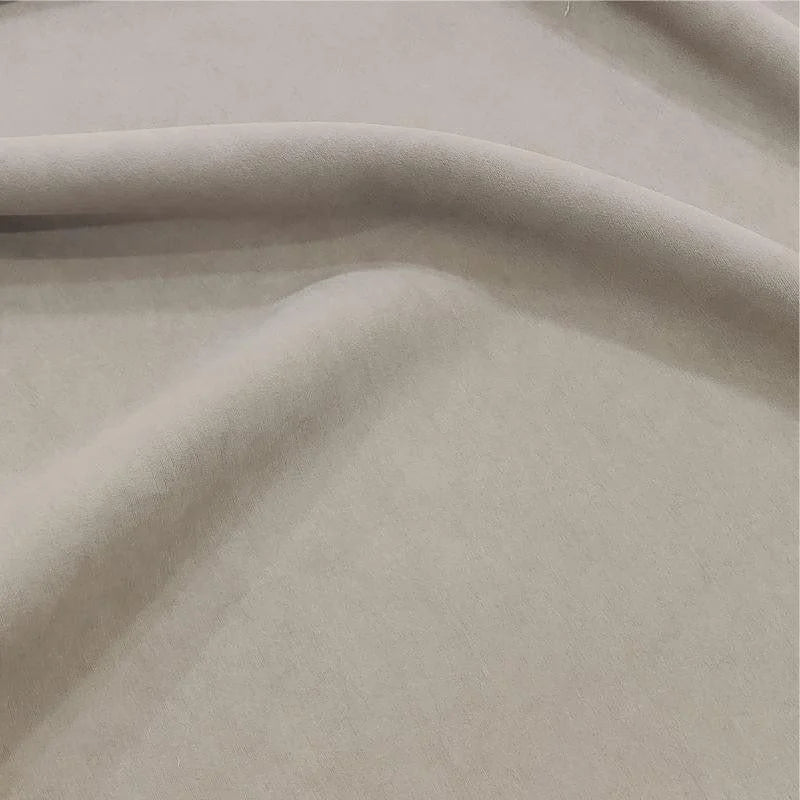 Image d'un tissu beige drapé avec élégance, idéal pour la couture de vêtements ou de décorations intérieures, offrant une surface douce et uniforme, parfaite pour des créations sophistiquées.