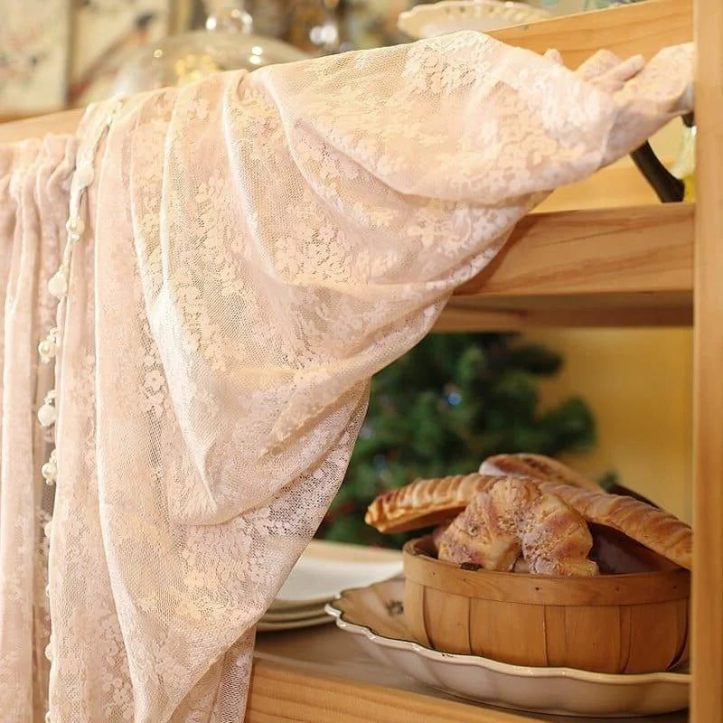 Rideau décoratif beige posé sur une étagère en bois, avec un panier de viennoiseries à proximité, idéal pour ajouter une touche élégante et chaleureuse à votre intérieur. Arrière-plan flou avec un arbre de Noël.