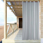 Rideau d'extérieur gris sur une terrasse en bois près de la plage, parfait pour créer un espace ombragé et intime. Solution idéale pour embellir et protéger un espace extérieur tout en conservant une ambiance moderne et élégante.