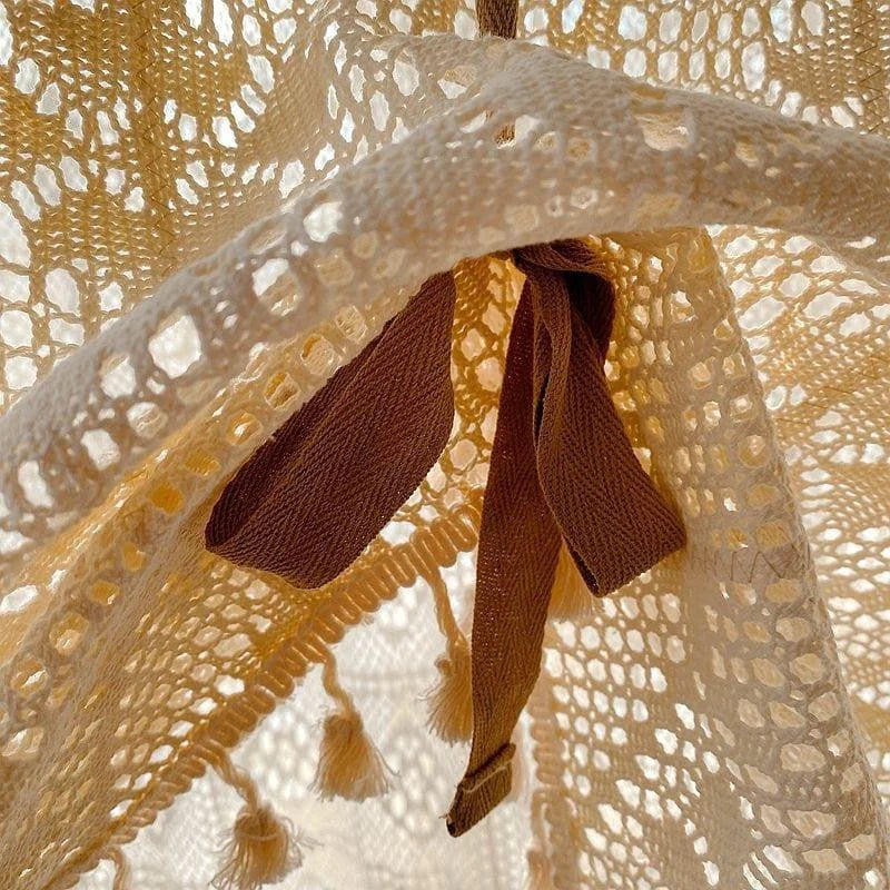 Gros plan sur un motif délicat de dentelle beige, avec des détails de pompons et des rubans marron, créant une ambiance élégante et raffinée. Idéal pour ajouter une touche sophistiquée à la décoration intérieure ou à la mode.